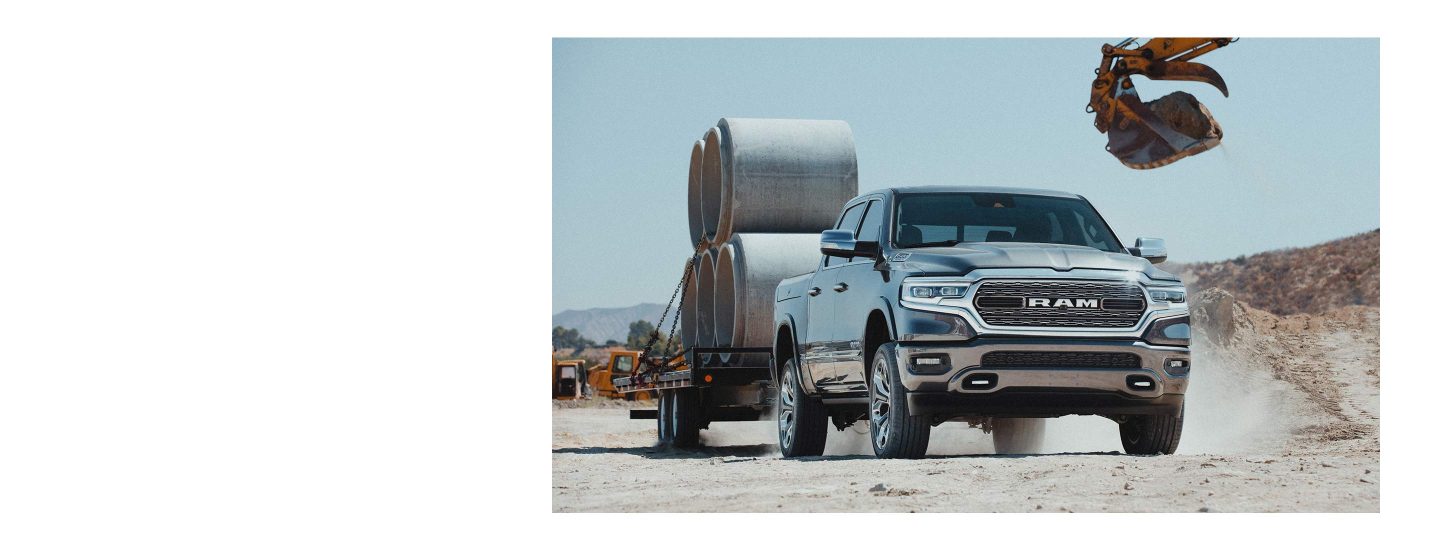 The 2022 Ram 1500 on a construction site towing a trailer stacked with concrete forms.